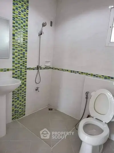 Modern bathroom with sleek shower and stylish green tile accents.