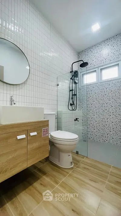 Modern bathroom with glass shower, wooden vanity, and stylish tile design.