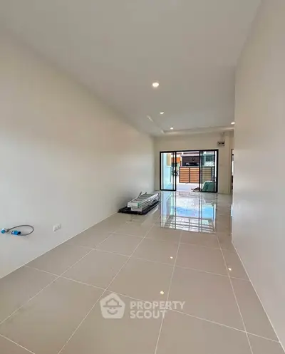 Spacious modern living room with glossy tiled floors and large sliding glass doors leading to a balcony.