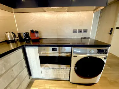 Modern kitchen with sleek appliances including oven and washing machine, stylish cabinetry, and elegant countertops.