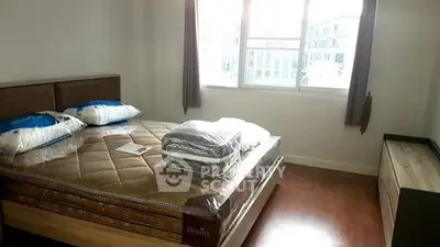 Cozy bedroom with large window and natural light, featuring a comfortable bed and modern furnishings.