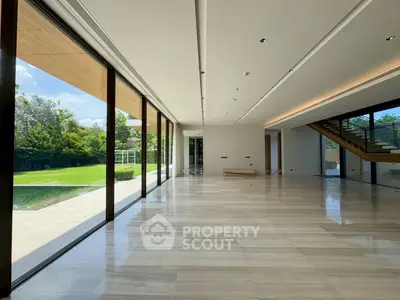 Spacious modern living room with floor-to-ceiling windows and garden view.