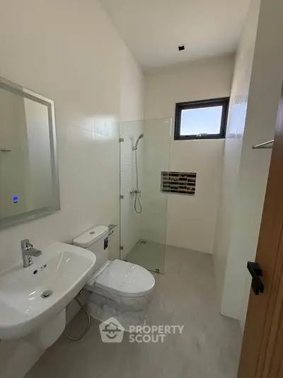 Modern bathroom with sleek fixtures and glass shower enclosure in a minimalist design.