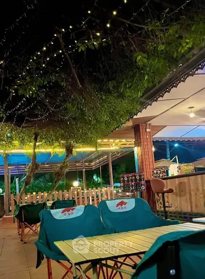 Charming outdoor seating area with cozy lighting and lush greenery, perfect for relaxing evenings.
