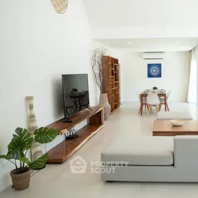 Modern living room with sleek furniture and open layout, featuring a TV and dining area.