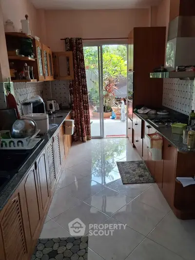 Charming kitchen with open layout and garden view, featuring wooden cabinets and modern appliances.