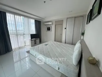 Spacious modern bedroom with large windows and natural light in a high-rise apartment.