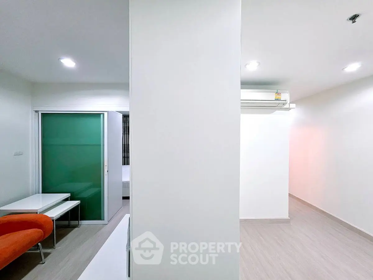 Modern minimalist apartment interior with sleek design and bright lighting, featuring a sliding glass door and air conditioning.