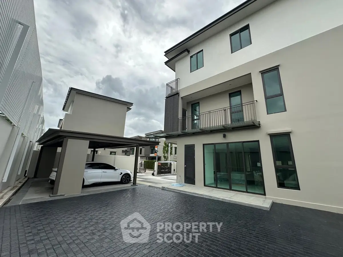 Modern three-story house with sleek design and carport in upscale neighborhood.