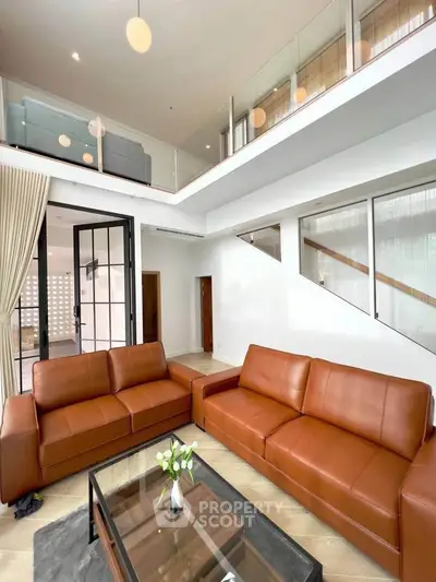Spacious modern living room with high ceilings and elegant leather sofas in a luxurious home.