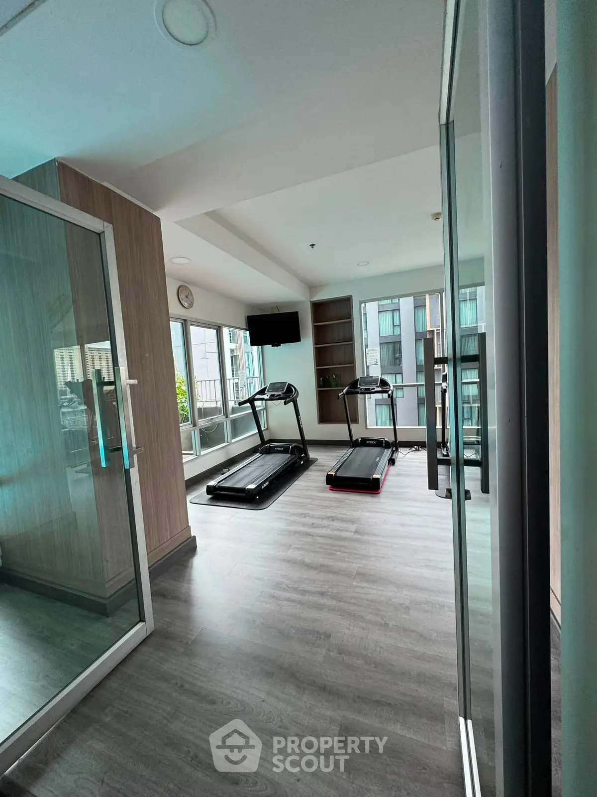 Modern gym with treadmills and large windows in a residential building