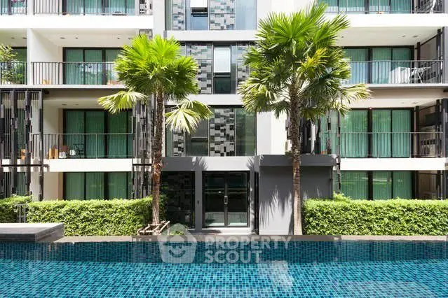 Modern apartment building with lush greenery and inviting pool area.