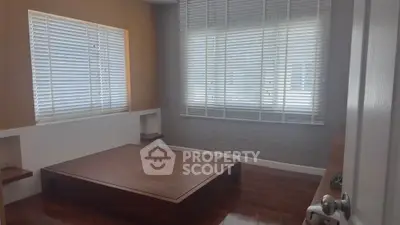Spacious minimalist bedroom with wooden platform bed and large windows