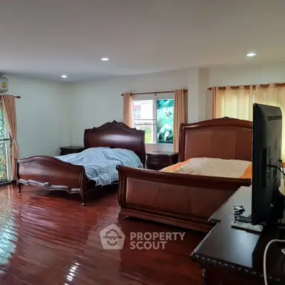 Spacious bedroom with elegant wooden furniture and polished floors, offering a cozy and luxurious ambiance.
