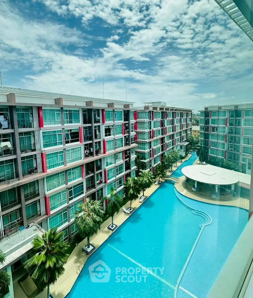 Luxurious apartment complex with stunning pool and modern architecture under clear blue skies.