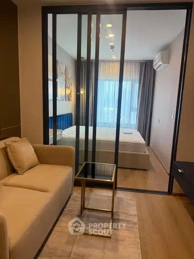 Modern apartment with glass partition, cozy living area, and stylish bedroom.