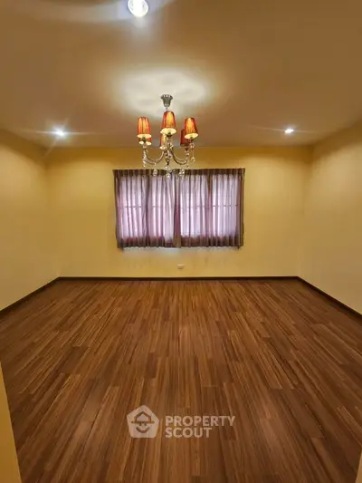 Spacious empty room with elegant chandelier and wooden flooring