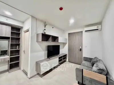 Modern living room with sleek furniture and wall-mounted TV in a cozy apartment.