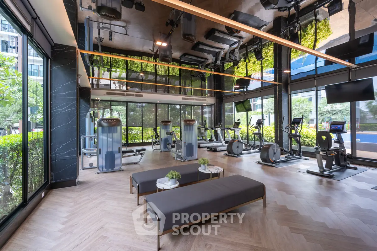Luxurious gym with modern equipment and stunning garden views in upscale residential building.