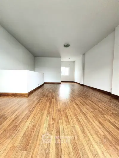 Spacious empty room with wooden flooring and bright natural light