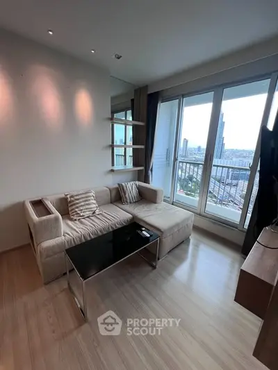 Modern living room with city view, featuring a cozy beige sofa and sleek glass coffee table.