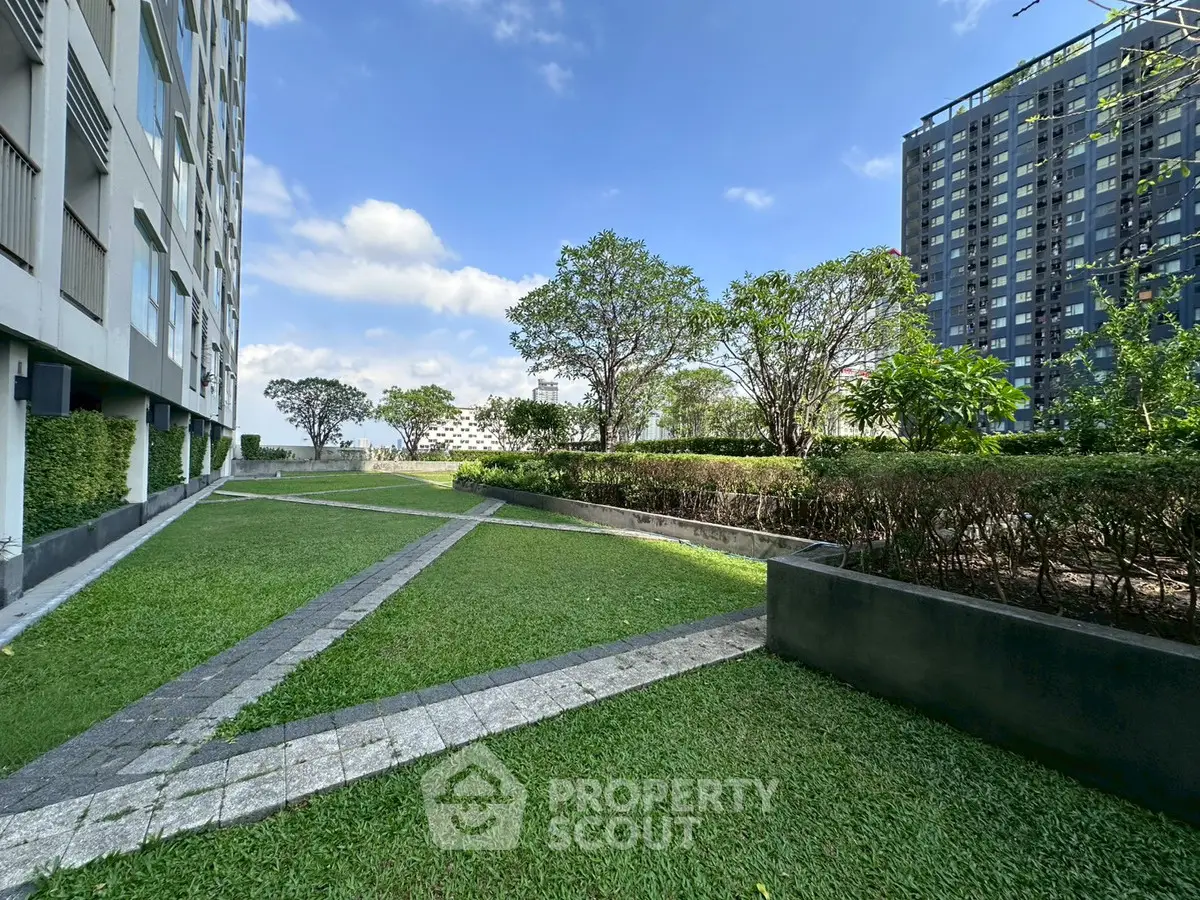 Modern apartment building with lush landscaped garden and clear blue sky.