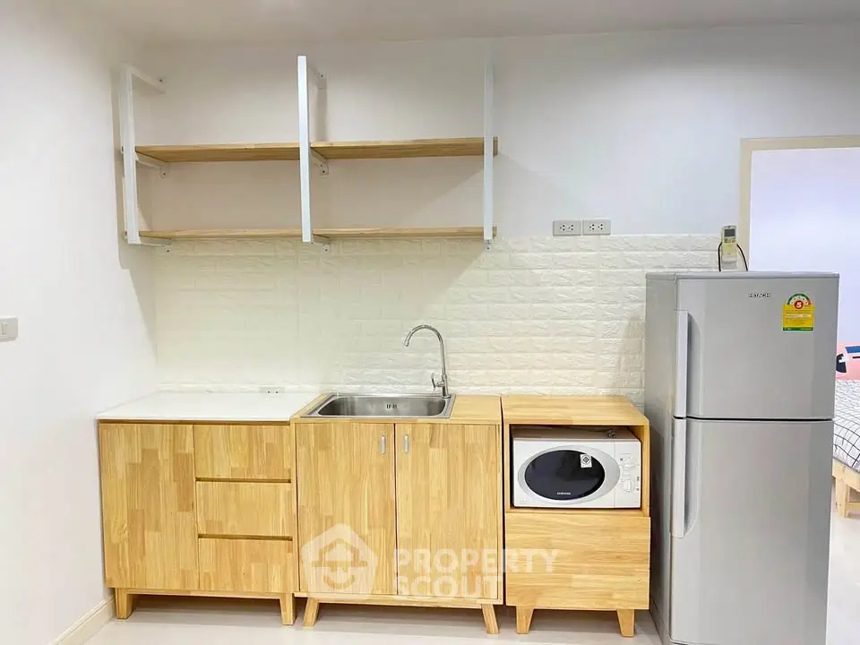 Modern kitchen with wooden cabinets, sink, washing machine, and fridge in a compact layout.
