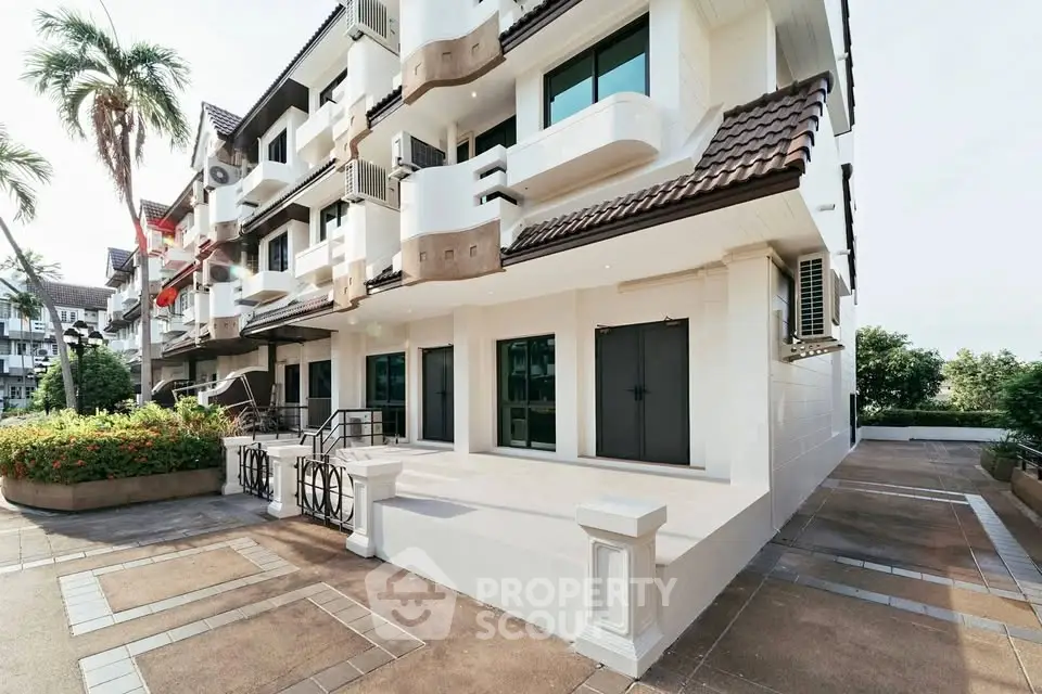 Charming multi-story residential building with balconies and lush landscaping in a serene neighborhood.
