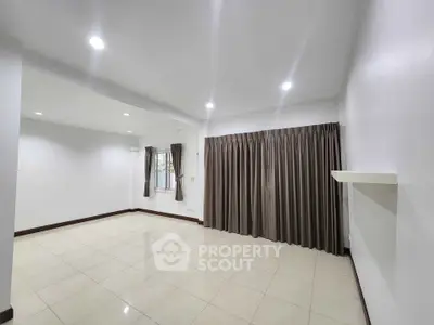 Spacious empty living room with tiled flooring and large windows, perfect for customization.