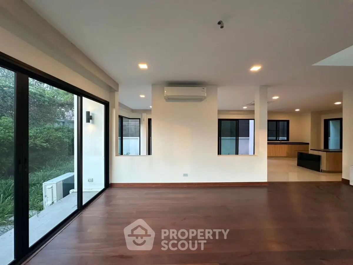 Spacious modern living room with hardwood floors and large windows overlooking garden