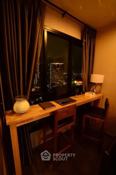 Cozy study nook with city view, featuring a wooden desk and elegant lighting.