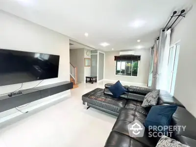 Spacious modern living room with sleek black leather sectional and wall-mounted TV