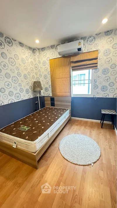 Cozy bedroom with stylish wallpaper and air conditioning, perfect for a comfortable living experience.