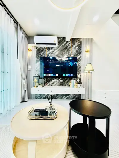 Luxurious modern living room with stylish decor and wall-mounted TV, featuring elegant lighting and sleek furniture.