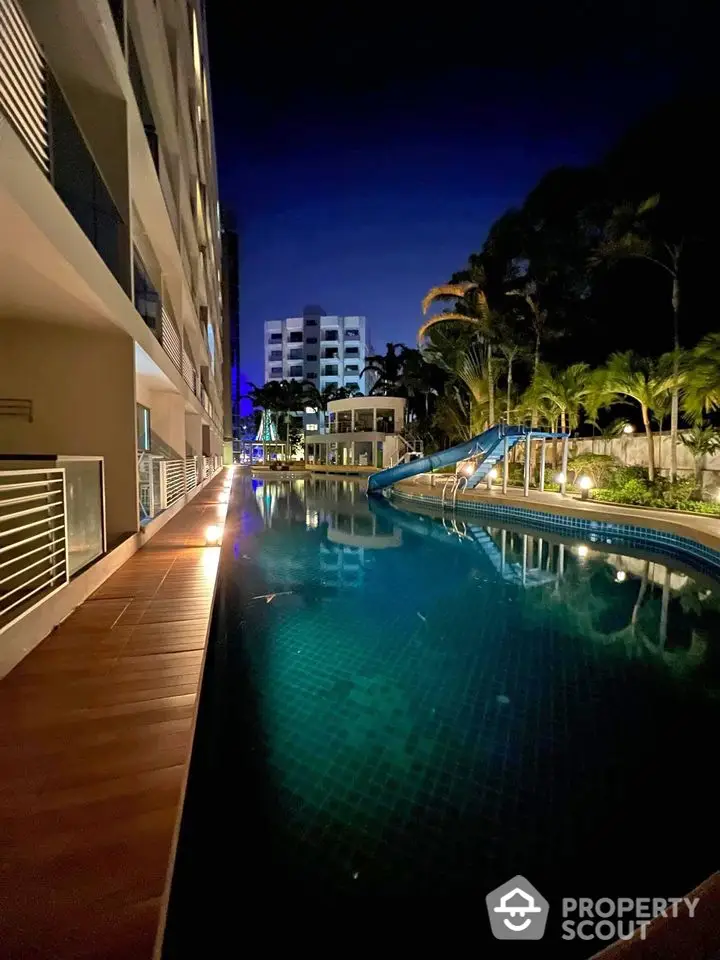 Luxurious apartment complex with stunning night pool view and lush greenery.