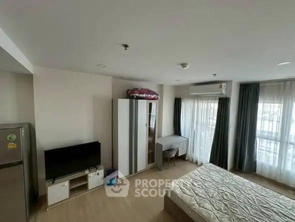 Modern bedroom with natural light, featuring a wardrobe, desk, and TV, ideal for urban living.