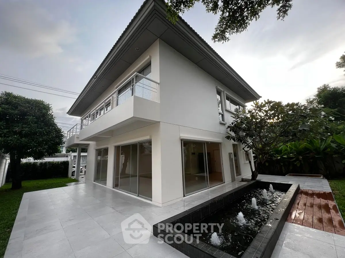 Modern two-story house with sleek design and elegant water feature in lush garden setting.