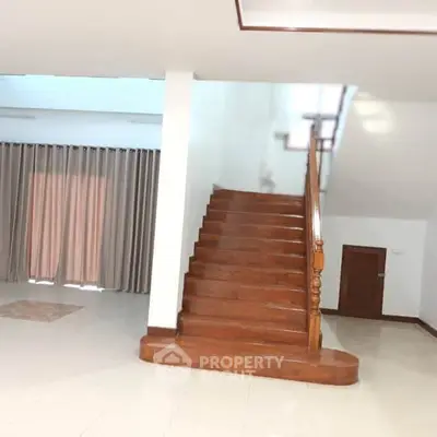 Elegant staircase in spacious living area with large windows and curtains