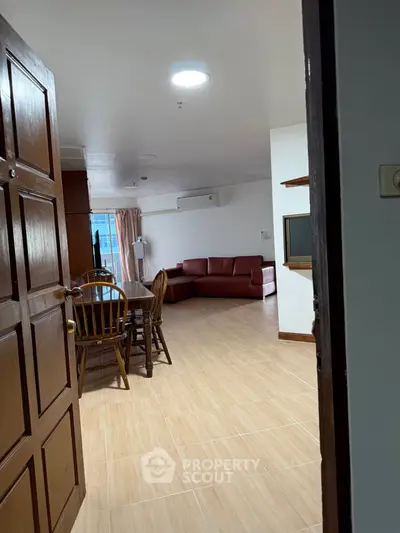 Spacious living room with wooden dining set and red sofa, perfect for family gatherings.