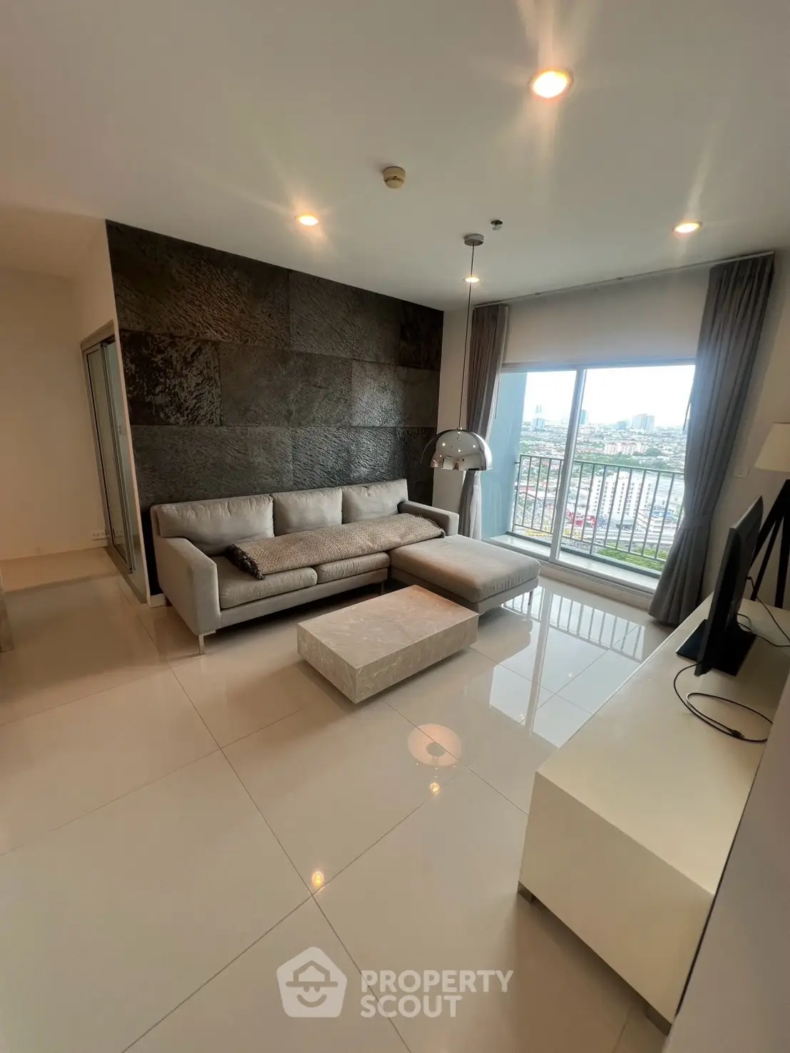 Modern living room with sleek design and city view from large window, featuring stylish furniture and elegant decor.
