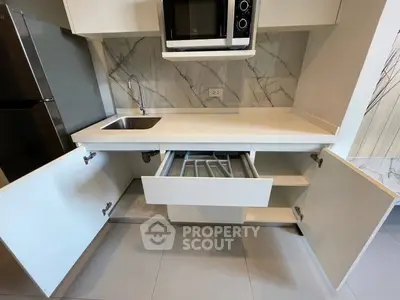 Modern kitchen with sleek cabinetry, built-in microwave, and marble backsplash