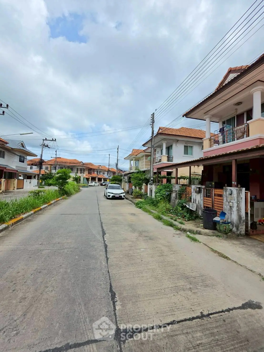 Charming suburban street with modern houses and lush greenery under a cloudy sky.