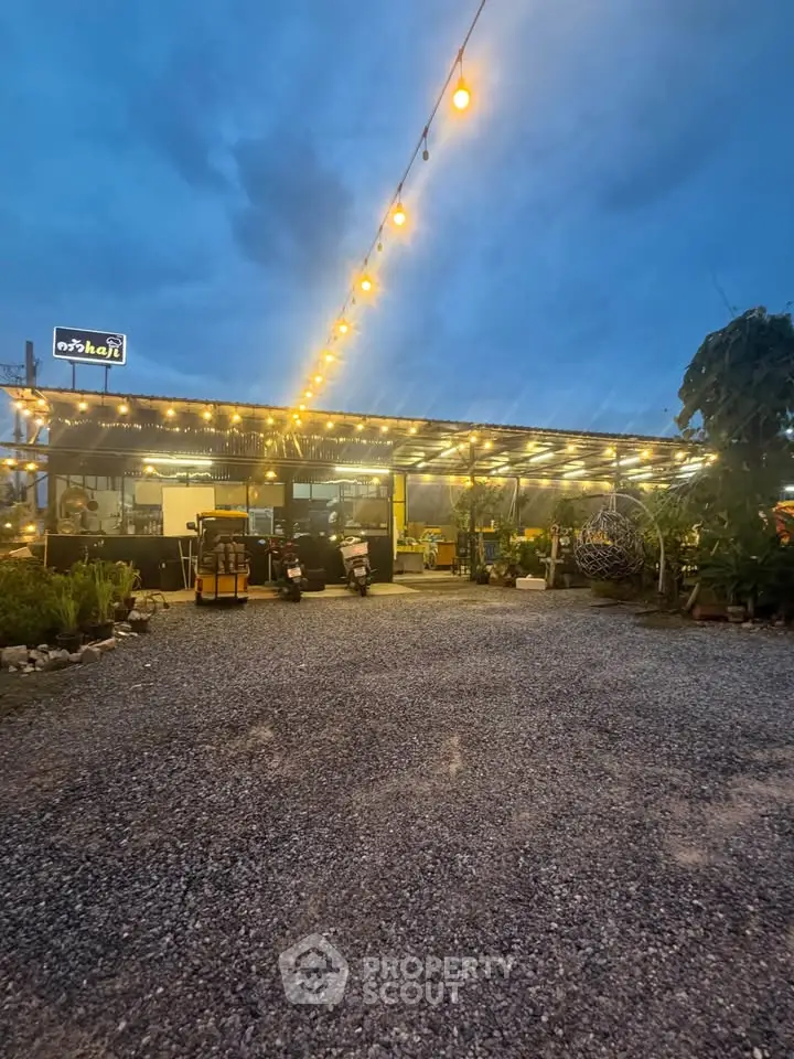 Charming outdoor cafe with string lights and gravel pathway, perfect for evening gatherings.