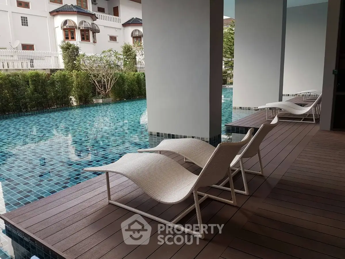 Luxurious poolside area with stylish lounge chairs and serene water view.