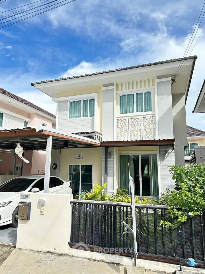 Charming two-story house with carport and lush greenery in a serene neighborhood.