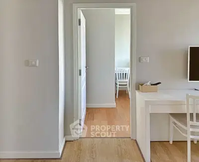 Modern minimalist interior with wooden flooring and white furniture, showcasing a bright and airy living space.