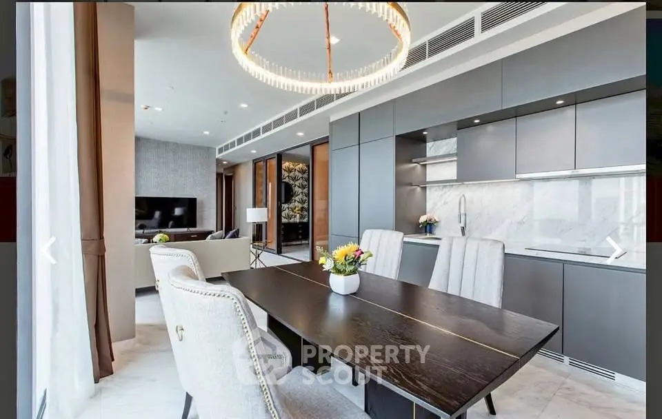 Luxurious open-plan living and dining area with modern kitchen and elegant chandelier.