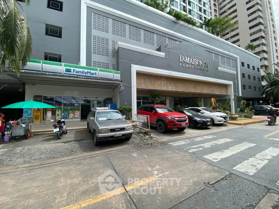 Modern building exterior with retail shops and parking area in urban setting.
