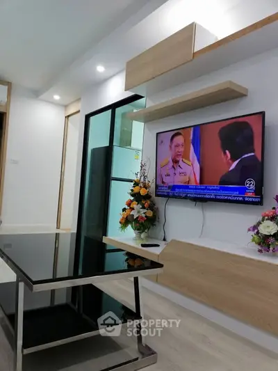 Modern living room with sleek black glass table and wall-mounted TV in stylish apartment.