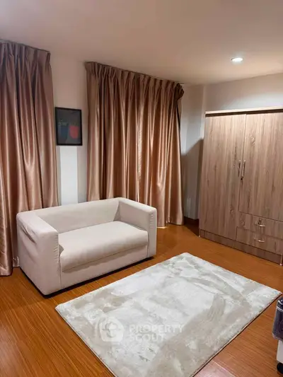 Cozy living room with modern sofa, elegant curtains, and wooden flooring for a warm ambiance.